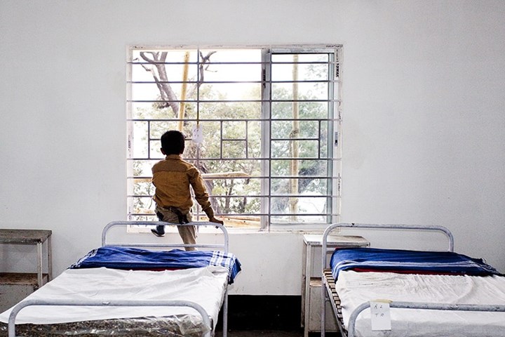 a boy sitting on his bed looking out of the window